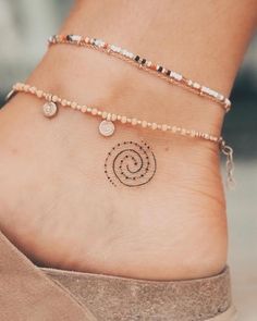 a woman's foot with a small tattoo on the ankle that has a spiral design