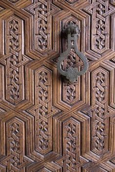 an ornate wooden door with metal handle on it