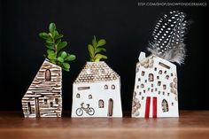 three small houses with plants in them on a wooden table next to a black background