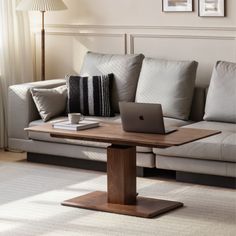 a laptop computer sitting on top of a wooden table in front of a white couch