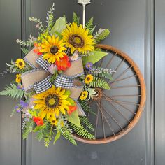 a wreath with sunflowers and greenery hangs on a door handle, next to a bicycle wheel