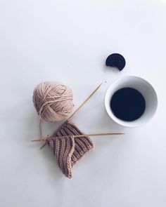 two skeins of yarn next to a cup of coffee on a white surface