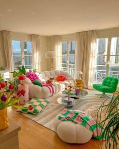 a living room filled with lots of furniture next to large window covered in white curtains