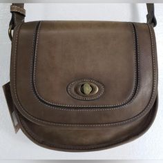 Justin Dark Brown Leather Saddle Bag Crossbody - Purse. Fold Over Top Flap With Metal Turn Button. Interior Has 1 Large Zip Pocket And 2 Medium Slip Pockets. Burnished Brass Colored Hardware. Measures 8.5" T X 9" W At The Bottom - 2.5" - 3.25" D. Has 53" Adjustable Strap. Brand New-Original Tags Vintage Satchel With Metal Hardware, Vintage Shoulder Bag With Metal Hardware, Retro Crossbody Satchel For Errands, Retro Crossbody Bag With Brass Hardware, Crossbody Saddle Bag With Turn-lock Closure, Everyday Crossbody Saddle Bag With Turn-lock Closure, Retro Saddle Bag For Daily Use, Vintage Satchel Shoulder Bag With Turn-lock Closure, Retro Crossbody Saddle Bag For Everyday Use