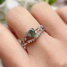 a close up of a person's hand wearing a ring with an oval green stone