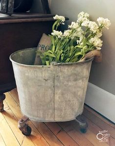 a bucket with flowers in it sitting on the floor