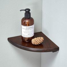 a bottle of soap sitting on top of a wooden shelf next to a pine cone