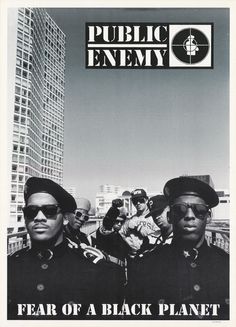 two black men wearing hats and sunglasses are standing in front of a tall building with the words public enemy on it