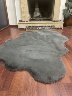 a large gray rug on the floor in front of a fire place