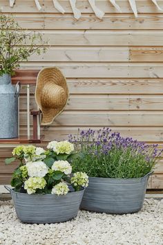 two planters filled with flowers next to a wooden wall