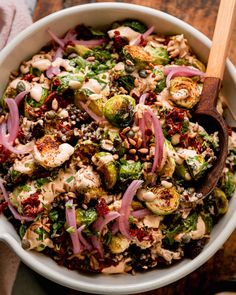 a salad with red onions, broccoli and other vegetables in a white bowl