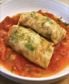 two enchiladas sitting in a white bowl on top of a wooden table