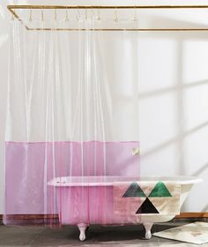 a bath tub sitting in front of a window next to a rug and towel on the floor