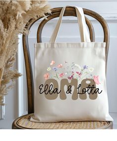 a tote bag sitting on top of a chair next to some dried grass and flowers