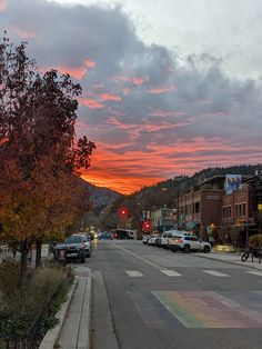 a street with cars parked on the side of it under a colorful sky at sunset