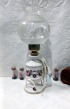 an old fashioned glass lamp on top of a white table with other items around it