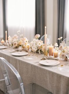 a long table is set with white flowers, candles and plates for an elegant dinner