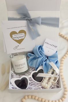 a gift box with sunglasses, candle and necklace