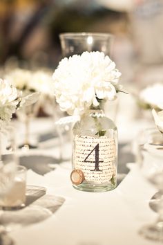 the table is set with clear vases and white flowers