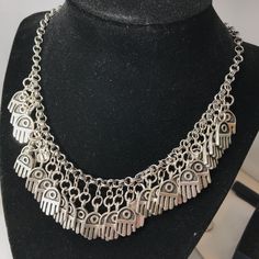 "This beautiful necklace and earring set is inspired by Arabic iconography. The necklace is adjustable between 16\" to 20\". It also supports an accent chain dangling from the end of the necklace closure with a charm. The earrings are suspended from an ear wire. All of these pieces are pewter plated in a high quality silver for a long lasting finish. Another Arabic name for the hamsa (or khamsa) is the hand of Fatima, commemorating Fatima Zahra, the daughter of the Prophet Muhammad. Archaeologic Oxidized Finish Necklace For Festivals, Symbolic Metal Necklace With Silver Chain, Symbolic Metal Chain Necklace, Spiritual Metal Jewelry With Silver Chain, Festival Metal Charms Jewelry, Metal Pendant Charm Necklaces For Festivals, Silver Spiritual Choker Necklace, Silver Spiritual Charm Necklace, Spiritual Silver Choker Jewelry