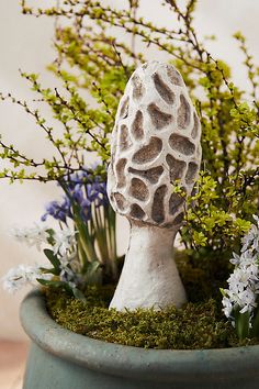 a planter filled with flowers and a mushroom like object in the middle of it