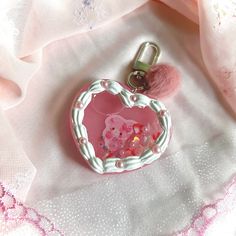 a pink heart shaped keychain sitting on top of a white cloth