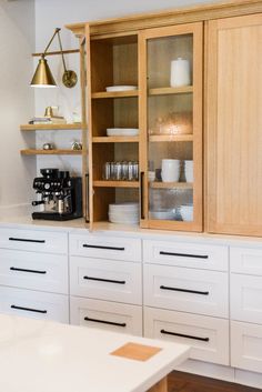 a kitchen with white cupboards and wooden shelves next to a coffee maker on the counter