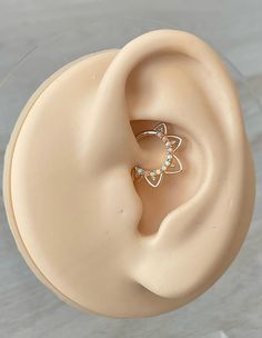 a pair of ear piercings on top of a plastic ring holder with clear crystal stones