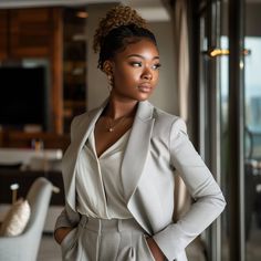 a woman standing in front of a glass door wearing a suit and heels with her hands on her hips