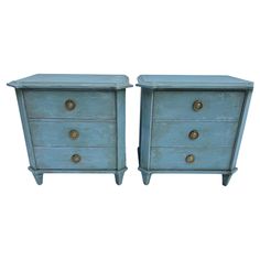 pair of blue painted nightstands with brass pulls and knobs on each drawer, side by side