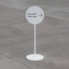 a white sign that says gallery this way on it's stand in an empty parking lot