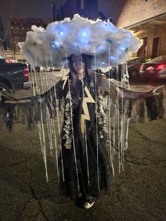 a woman dressed in black and white holding an umbrella over her head while standing on the street