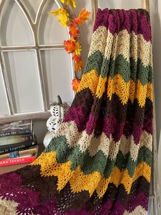 a crocheted blanket sitting on top of a chair next to a window with flowers