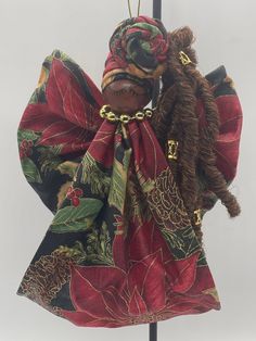 an angel ornament hanging on a pole with a red and green scarf around it's neck