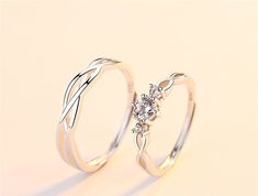 two silver rings with white diamonds on top and one has a flower in the middle