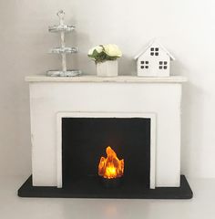 a white fireplace with a lit fire in it and some flowers on the mantel