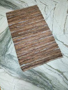 a brown rug sitting on top of a marble floor next to a wooden table and chair