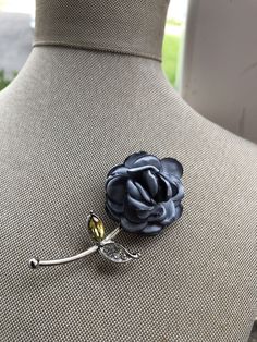 a blue flower brooch sitting on top of a mannequin's torso