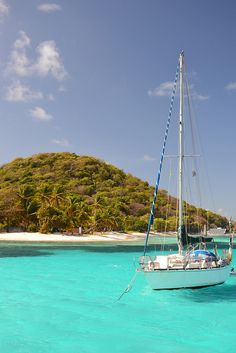 a sailboat floating in the ocean next to a small island