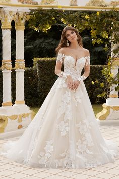 a woman in a wedding dress posing for the camera with her hands on her hips