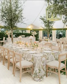 the tables are set up for an outdoor wedding reception with white linens and floral centerpieces