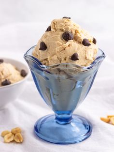 an ice cream sundae with chocolate chips in a blue glass bowl on a white tablecloth