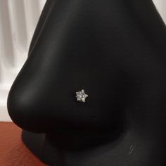 a small diamond ring sitting on top of a black mannequin's head