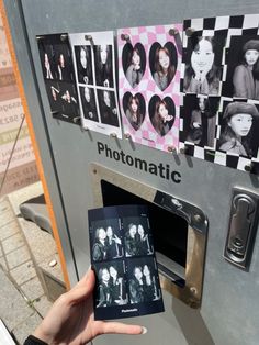 a person holding up a polaroid in front of a machine with pictures on it