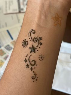 a woman's arm with a tattoo design on the wrist and stars around it