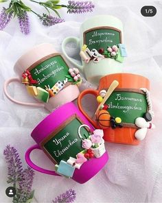 four coffee mugs with writing on them and some flowers in the middle one has a chalkboard