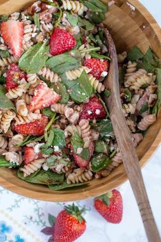 a wooden bowl filled with pasta salad and strawberries