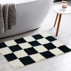 a black and white rug on the floor next to a bathtub