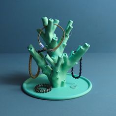 a green tree with rings and bracelets sitting on top of it's base