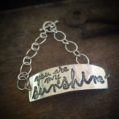 "\"You Are My Sunshine\". Are you singing already? This bracelet is a little piece of happy. This bracelet is lovingly made from recycled fine silver, and 2 sets of sterling silver chain. It is finished with a toggle clasp. The silver artwork charm is approximately 1 3/4 inches across and 1/2 inch wide. If you require a bracelet size other than a standard 7 inches, simply leave me a note during checkout with your desired size. Not familiar with fine silver? Here are the facts: Fine silver has a Inspirational Handmade Name Bracelet For Everyday, Everyday Inspirational Handmade Name Bracelet, Inspirational Handmade Name Bracelet, Meaningful Promise Bracelet For Mother's Day, Handmade Adjustable Meaningful Bracelets, Personalized Adjustable Sterling Silver Bracelet, Customized Sterling Silver Jewelry For Friendship, Meaningful Hand Stamped Jewelry For Friendship, Meaningful Adjustable Charm Bracelet